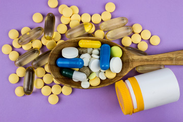 Capsules and tablets on wooden spoon. Medicine pharmaceutical theme. 