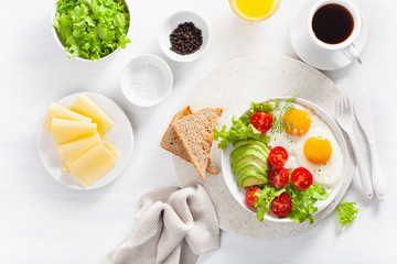 healthy breakfast flat lay. fried eggs, avocado, tomato, toasts and coffee