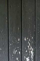 Grungy background of peeling flaking black paint on wooden boards