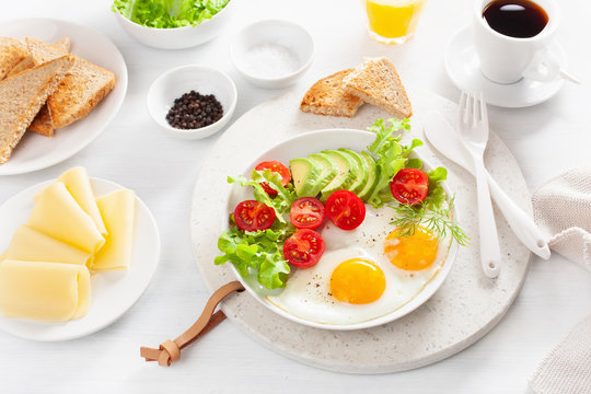healthy breakfast with fried eggs, avocado, tomato, toasts and coffee