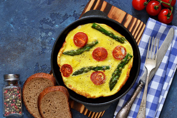 Good morning. Omelet with asparagus and tomatoes for breakfast with toast and coffee on a blue background.