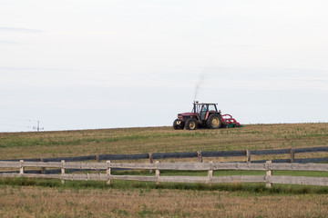Fototapeta premium tractor at work on a cultivated field cloud of smoke comes out of the drainpipe. Industrial agriculture in northern Europe