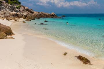 A woman is swimming in the shallow water of Pulau Rawa. The crystal clear water, azure blue ocean and powdery white sand makes this paradise one of the best beaches within the Perhentian archipelago.