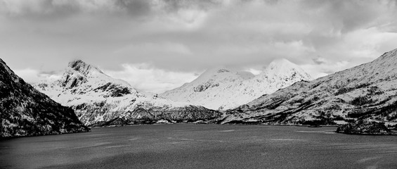 Landscape with beautiful winter lake and snowy mountains at Lofoten Islands in Northern Norway. Panoramic view, black and white