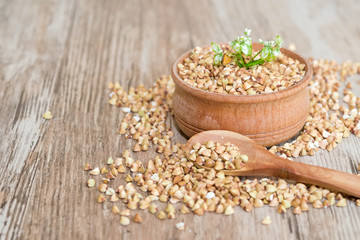 Natural organic green buckwheat in wooden plate on wooden background, selective focus, healthy eating concept 

