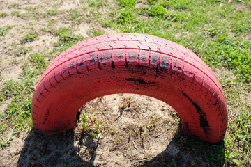 Red painted tire on playground grass