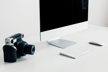 Close-up on camera on white desk with desktop computer and keyboard in work area interior. Real...