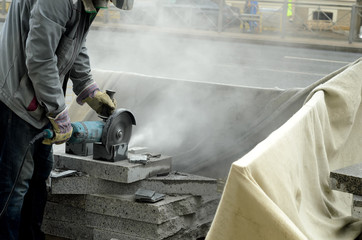 The worker cuts a big powerful angle grinder paving slabs.