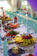 Obraz na płótnie Canvas a furnished table for a party. On the table are clean dishes, fresh fruit and drinks. style in tiffany color