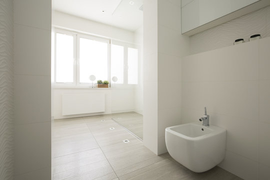 Toilet in white spacious bathroom interior with windows. Real photo