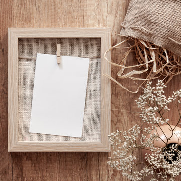 Wooden Autumn Desk With A Dried Decoration, A Jute Bag, A Vase With White Flowers And A Mockup Frame