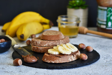 Grilled toast with chocolate paste and banana for breakfast on a concrete background.