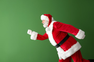 Portrait of running Santa Claus on color background