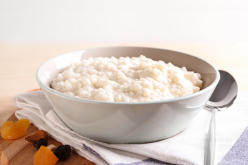 Delicious rice pudding in bowl on wooden board