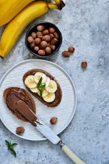 Grilled toast with chocolate paste and banana for breakfast on a concrete background.