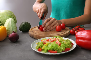 Woman cutting tomatoes for salad on wooden board