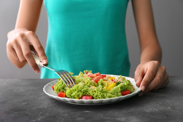 Woman eating healthy fresh salad at table