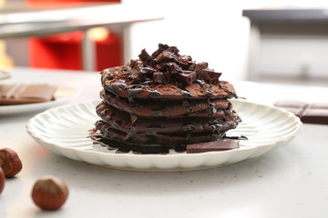 Plate with tasty chocolate pancakes on white table, closeup