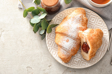 Plate with tasty croissant on light table