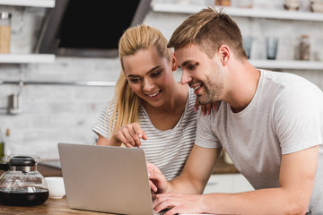 couple looking at laptop together in kitchen