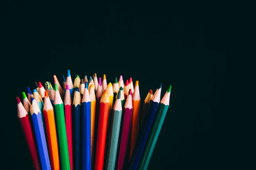 Colored pencils isolated on black background.
