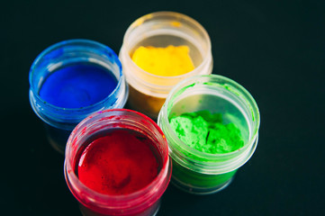 Gouache on black background. Blue, yellow and green red gouache. A set of gouache