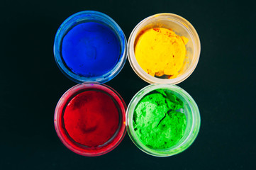 Gouache on black background. Blue, yellow and green red gouache. A set of gouache