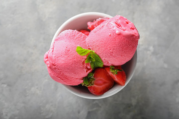 Bowl with delicious strawberry ice-cream on grey table