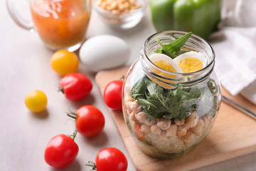 Delicious vegetable salad with egg in mason jar on wooden board