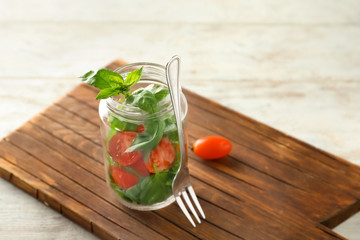 Delicious vegetable salad in mason jar on wooden board