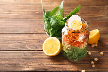 Delicious vegetable salad with egg in mason jar on wooden table