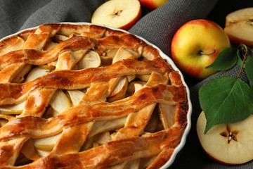 Dish with delicious apple pie on table