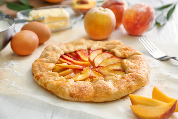 Parchment with delicious peach galette on white table