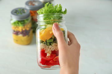Woman holding mason jar with delicious vegetable salad, closeup