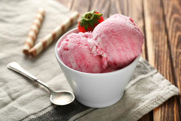 Bowl with delicious strawberry ice-cream on wooden background, closeup