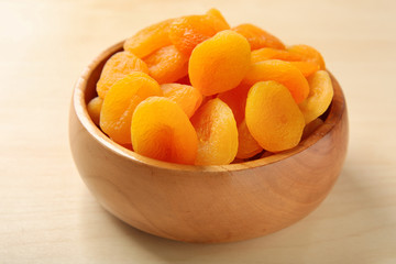 Bowl with dried apricots on wooden table