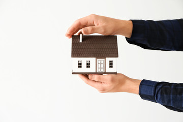 Man holding house model on light background
