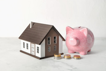 House model, piggy bank and coins on white table. Mortgage concept