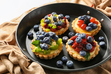 Delicious tarts with fruits and berries on pan
