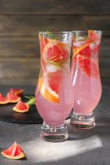 Fresh grapefruit cocktail with rosemary in glasses on grey table
