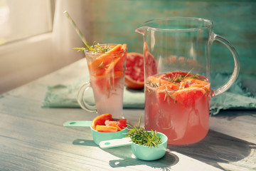 Fresh grapefruit cocktail with rosemary in glassware on white table