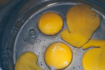 Broken eggs with yolks in a saucepan for cooking dough