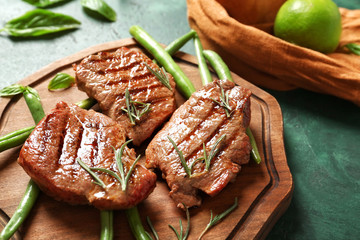Tasty grilled steaks with green beans and rosemary on wooden board