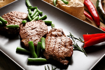 Tasty grilled steaks with green beans on plate