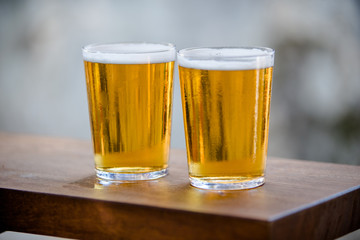 Two glasses of beer are on the bar 