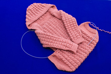 Children's knitted clothes on blue background