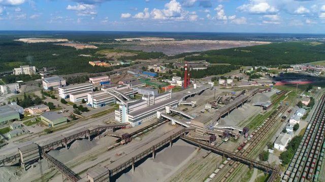 Logistics in manufacture, aerial view of freight trains near factory, laden with granite and marble, industrial landscape.