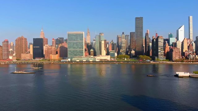Aerial Drone Footage panning left of New York City Manhattan skyline over East River viewed from Gantry Plaza State Park in Long Island City