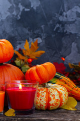 Autumn ripe of pumpkins with glowing candles on wooden table, low key image