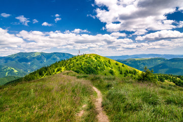Spring landscape with grassy meadows and the mountain peaks, blue sky with clouds in the background. The Donovaly area in Velka Fatra National Park, Slovakia, Europe.